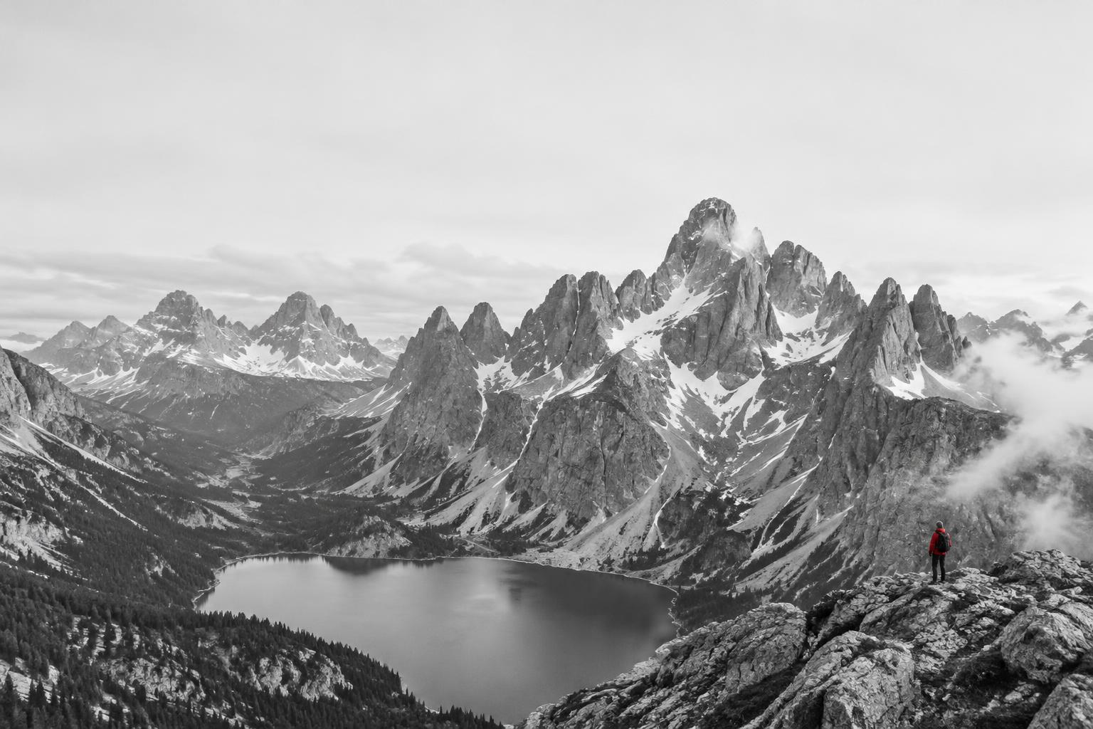 A lone adventurer above an alpine lake in the Dolomites